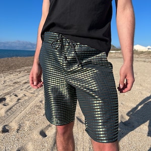 May include: Black and green patterned swimming shorts with a drawstring waist.