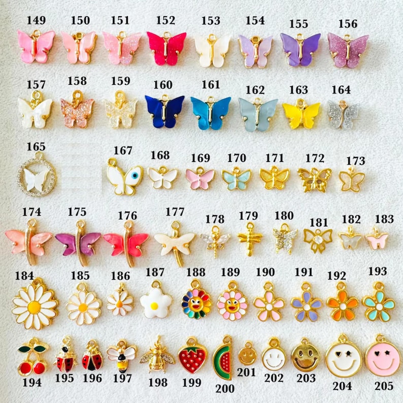 May include: A collection of colorful charms in various shapes, including butterflies, flowers, and fruit. The charms are in shades of pink, purple, blue, yellow, and gold. Each charm has a small loop for attaching to jewelry or other crafts.