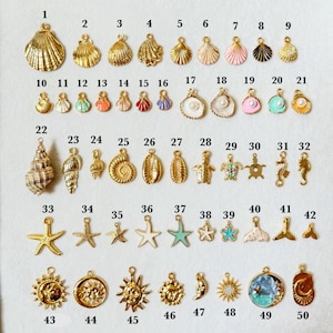 May include: A collection of 50 gold-toned and colorful seashell, starfish, and ocean-themed charms. The charms vary in size and design, including shells, seahorses, and suns, perfect for jewelry making.