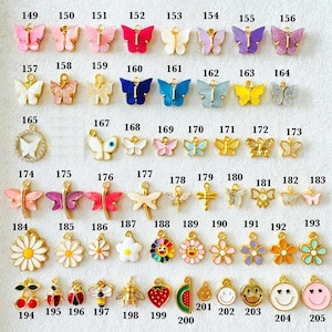 May include: A collection of small metal and enamel charms arranged in rows, each labeled with a number from 149 to 205. The charms include various butterfly shapes, flowers, insects, fruits, and smiley faces in assorted colors and finishes.