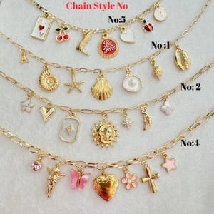 K&ouml;nnte beinhalten: Goldfarbene Kettenhalsketten mit verschiedenen Anh&auml;ngern, darunter eine Spielkarte, Kirschen, ein Herz und ein Marienk&auml;fer. Die Halsketten sind mit Nummern und dem Text "Chain Style No" versehen.