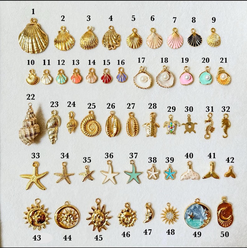 May include: A collection of fifty gold-toned metal charms in various shapes including seashells, starfish, seahorses, and suns, numbered one through fifty. Some charms feature enamel accents in pink, blue, white, and red, while others include small pearls.