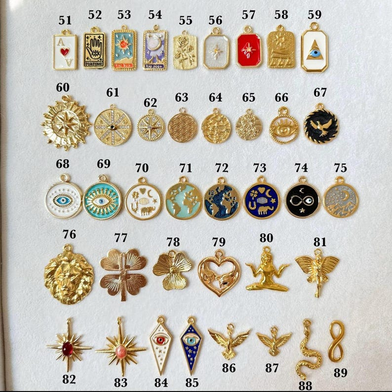 May include: A collection of metal charms numbered 51 through 89, featuring various shapes including rectangles, circles, hearts, stars, and figures. The charms display enamel details, symbols like eyes, celestial bodies, and animals in gold tones.