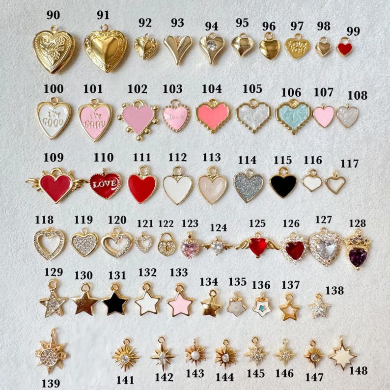 May include: A collection of gold-toned and colorful charms in various shapes, including hearts, stars, and lockets. Some charms feature glitter, enamel, and the word "LOVE". Ideal for jewelry making or crafting.