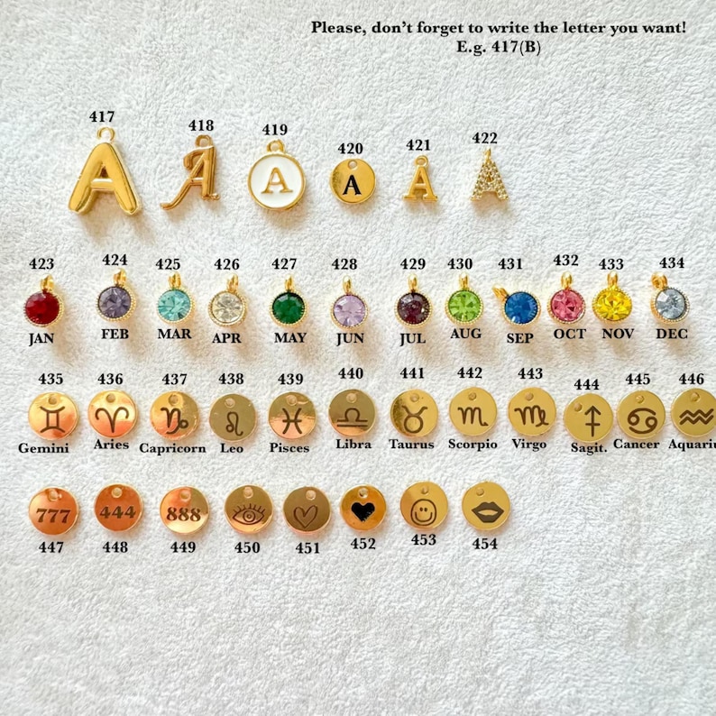May include: A collection of gold-colored charms and pendants. The image includes letter charms, birthstone pendants, zodiac sign charms, and other decorative charms. Text on the image reads "Please, don't forget to write the letter you want! E.g. 417(B)".