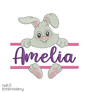 Könnte beinhalten: Stickerei mit einem grauen Hasen, der über einer rosa Linie lugt, mit dem Namen Amelia darunter in lila.