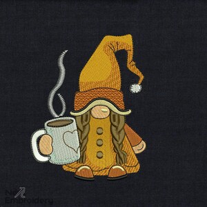 May include: A brown and yellow gnome with long brown braids is holding a white coffee mug with a brown liquid and steam coming from the top. The gnome is wearing a brown and yellow hat with a white pom-pom.