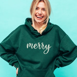 May include: A green hooded sweatshirt with the word "merry" written in white cursive on the front.