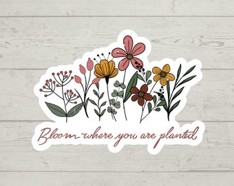 May include: A sticker with a floral design and the text "Bloom where you are planted". The flowers are pink, yellow, and red.