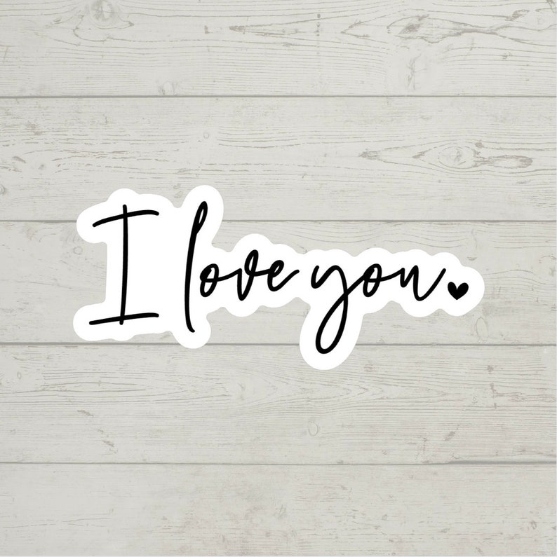 May include: White wood background with a black and white sticker that says "I love you" with a small heart.