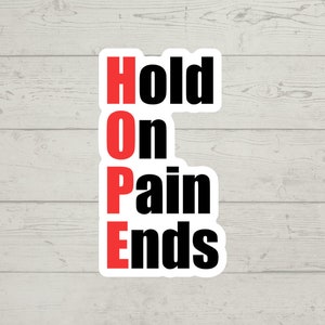 Pode incluir: Etiqueta branca com texto preto que diz "Hold On Pain Ends" com o "O" e o "E" em vermelho.