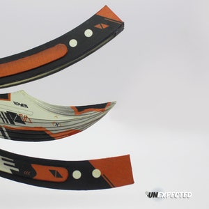 May include: A black and orange folding knife with a geometric pattern and the word "VOMER" printed on the blade.