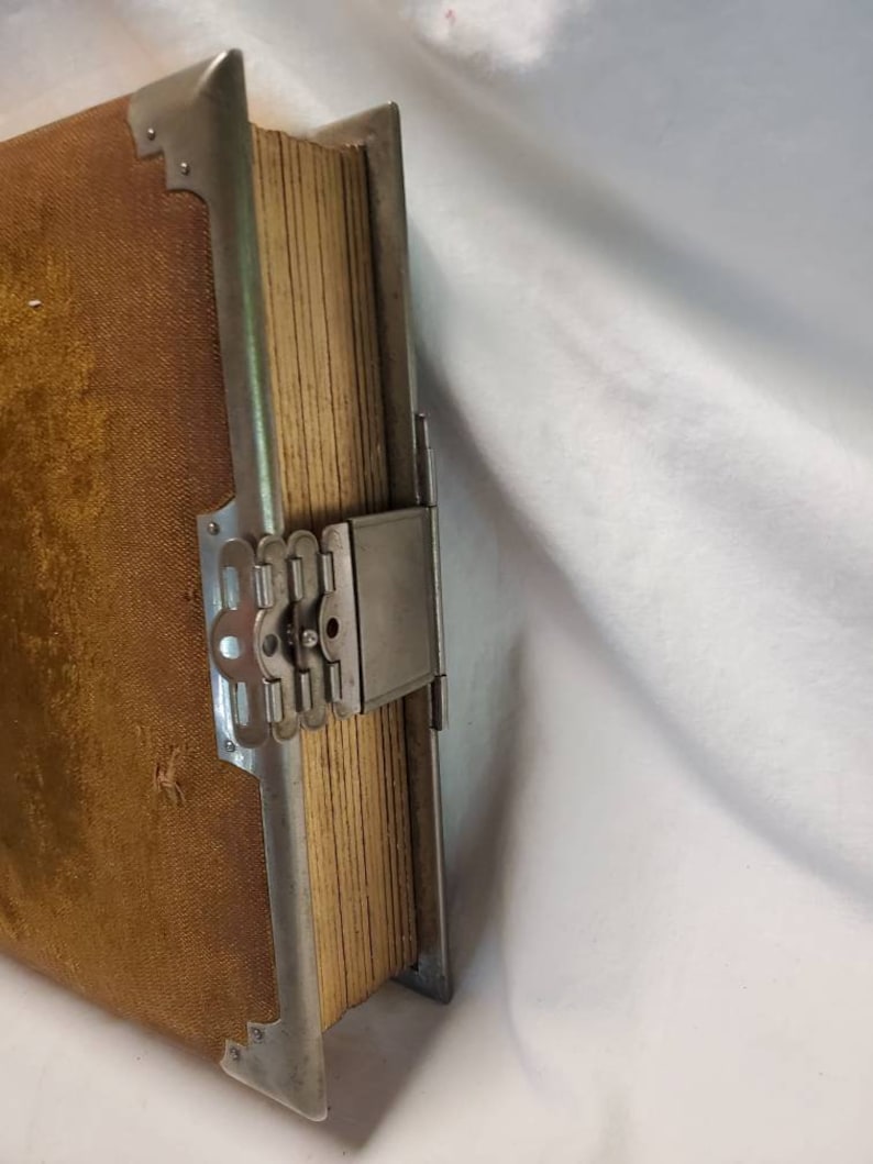 May include: A vintage photo album with a brown velvet cover and a silver metal clasp. The album is closed and the clasp is fastened.