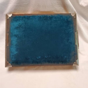 May include: A teal blue velvet-lined box with silver metal trim. The box has a hinged lid and a decorative design on the front.