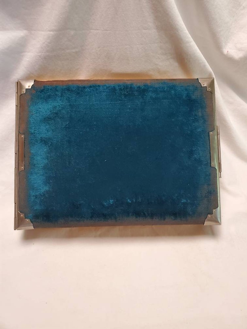 May include: A teal blue velvet-lined box with silver metal trim. The box has a hinged lid and a decorative design on the front.