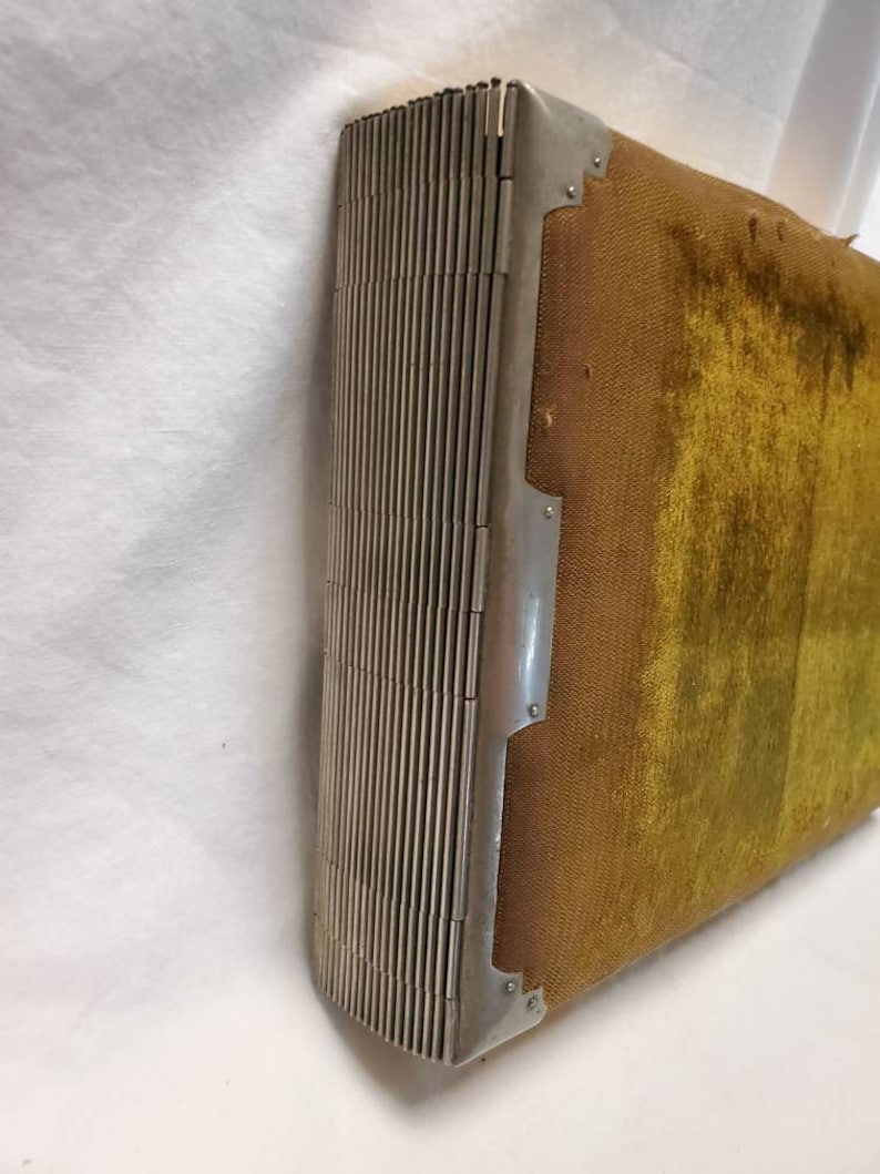May include: A vintage photo album with a green velvet cover and a silver metal hinge. The album is closed and the hinge is visible.