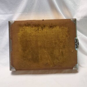 May include: A vintage photo album with a brown velvet cover and silver metal trim. The album has a clasp closure.