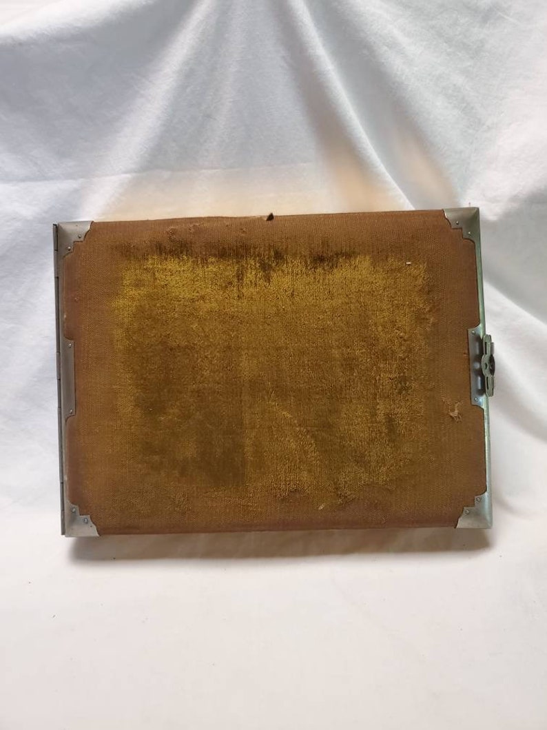May include: A vintage photo album with a brown velvet cover and silver metal trim. The album has a clasp closure.