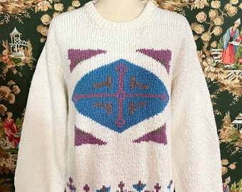 May include: White knitted sweater with a geometric pattern in purple, blue, and brown. The sweater has a crew neck and long sleeves.