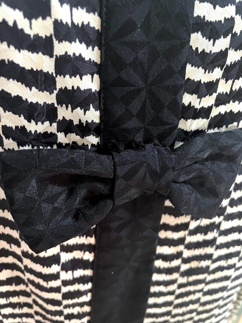 May include: A black and white striped dress with a black bow at the waist.