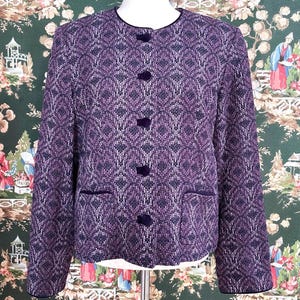 May include: A purple and black patterned blazer with velvet trim and buttons. The blazer has a classic style and is made of a soft, textured fabric.