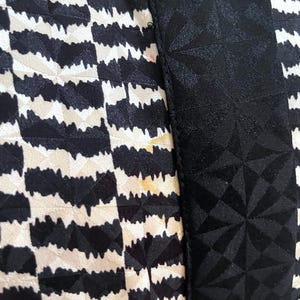May include: Close-up of a black and white patterned fabric with a black geometric pattern on the right side.