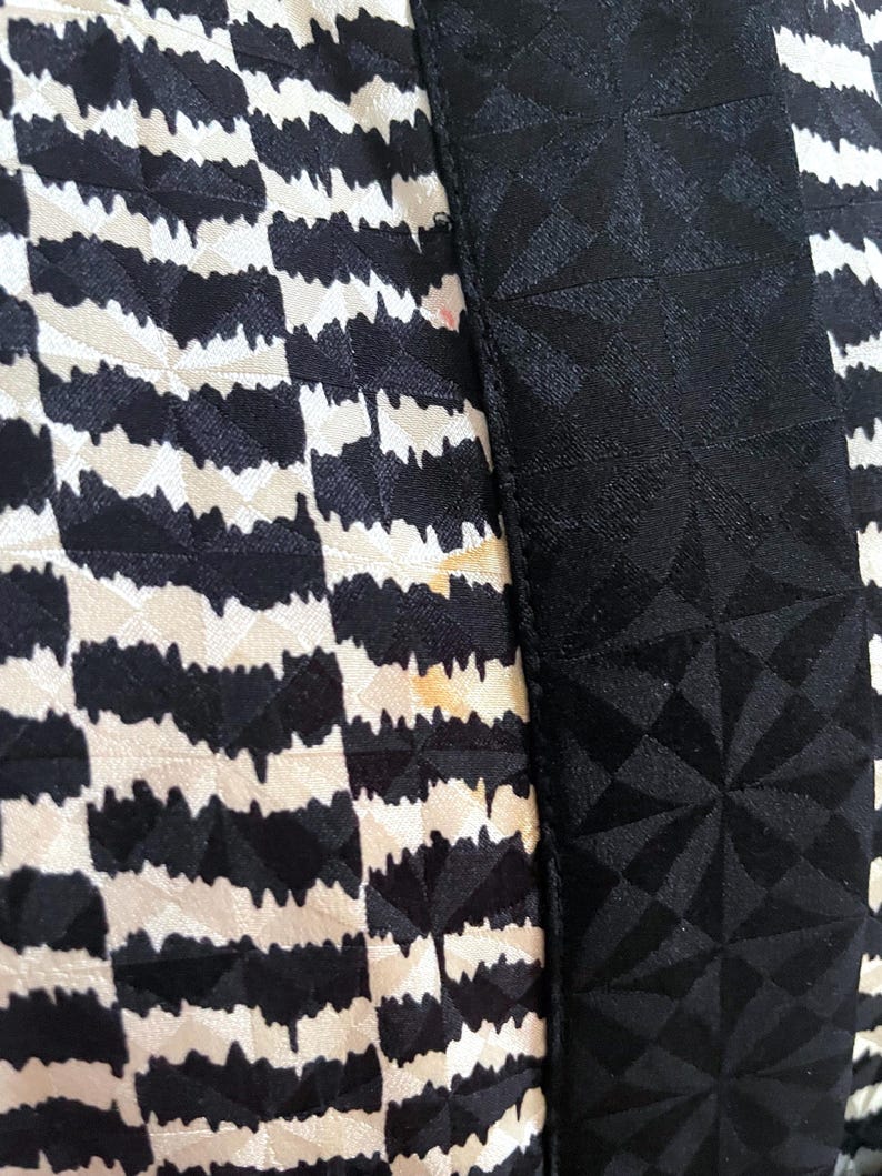 May include: Close-up of a black and white patterned fabric with a black geometric pattern on the right side.