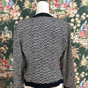May include: A black and white striped long-sleeved cardigan with a black trim around the neckline and hem.