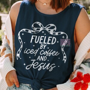 May include: A navy blue tank top with a white graphic that says "Fueled by iced coffee and Jesus" with a black and white checkered bow on top.