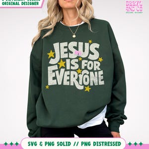 May include: Dark green sweatshirt with the text "JESUS IS FOR EVERYONE" in white, accented with yellow stars. The sweatshirt has a crew neck and long sleeves. The design includes the text "BEEZA AND CO ORIGINAL DESIGNER".