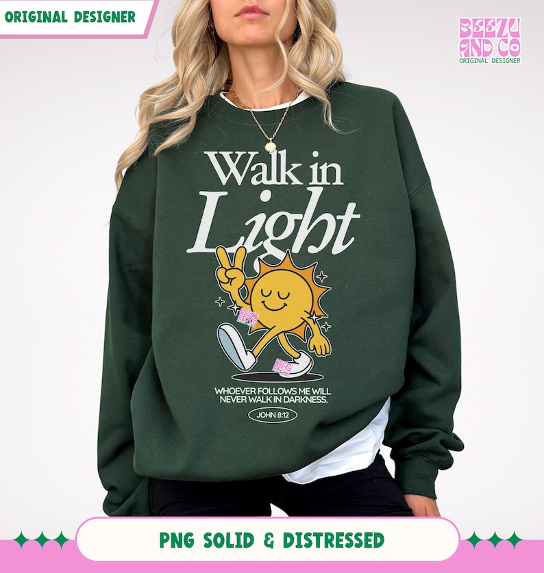 May include: Dark green sweatshirt with the text "Walk in Light" and a cartoon sun character giving a peace sign. The sweatshirt also features the text "WHOEVER FOLLOWS ME WILL NEVER WALK IN DARKNESS. JOHN 8:12".