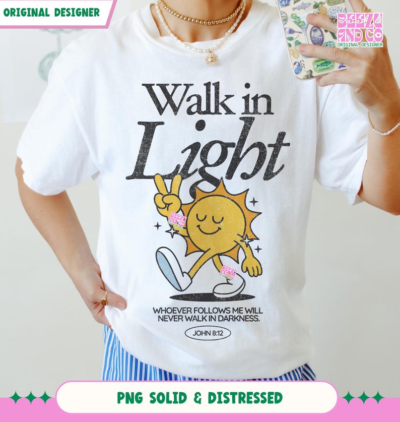 May include: White t-shirt with the text "Walk in Light" and a cartoon sun giving a peace sign. The sun has a smiling face and is wearing pink accessories. The shirt also features the Bible verse John 8:12.