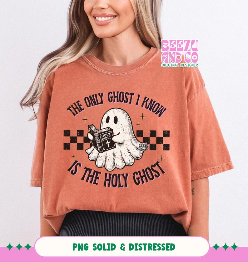 May include: A rust-colored short-sleeve t-shirt featuring a graphic of a white ghost holding a book labeled Holy Bible. The text reads The Only Ghost I Know Is The Holy Ghost, accompanied by a black and white checkered pattern and small stars.
