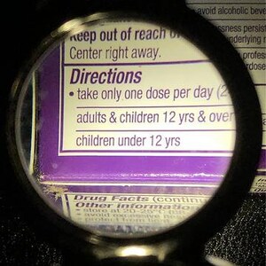 Puede incluir: Primer plano de una etiqueta morada y blanca con el texto "Directions" y "take only one dose per day (2)" y "adults & children 12 yrs & over" y "children under 12 yrs".