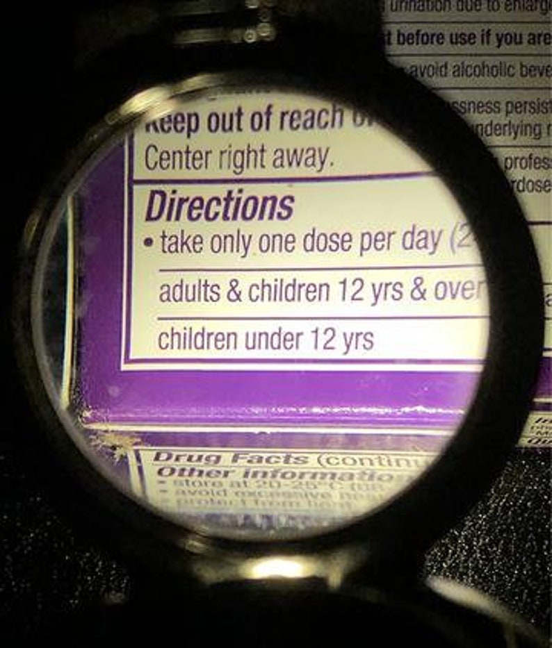 Puede incluir: Primer plano de una etiqueta morada y blanca con el texto "Directions" y "take only one dose per day (2)" y "adults & children 12 yrs & over" y "children under 12 yrs".