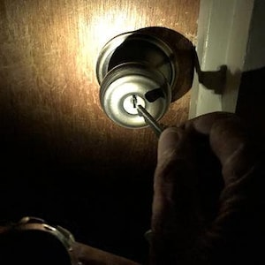 Puede incluir: Primer plano de una cerradura de puerta con un destornillador insertado en la cerradura.