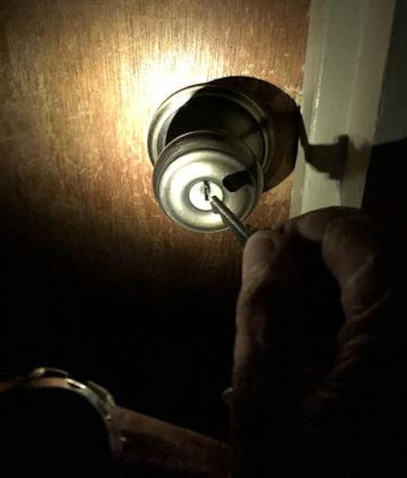 Puede incluir: Primer plano de una cerradura de puerta con un destornillador insertado en la cerradura.