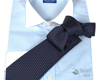 Puede incluir: Una camisa de vestir azul claro con cuello blanco y una corbata azul marino con lunares blancos. La camisa tiene el texto "Seven Arm New York" bordado en la parte delantera.