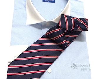 Puede incluir: Una camisa de vestir azul claro con cuello blanco y una corbata a rayas rojas y azul marino. La camisa tiene el texto "Seven For All Mankind" bordado en el lado izquierdo del pecho.
