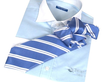 Puede incluir: Una camisa de vestir azul claro con cuello blanco y una corbata a rayas azules y blancas. La camisa tiene un logotipo que dice "Seven Oaks" en la parte delantera.