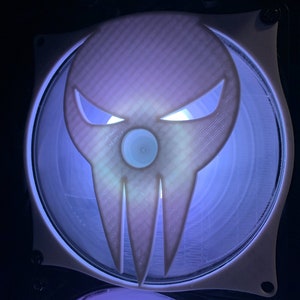 May include: A white computer fan with a 3D printed skull design. The skull is light purple with white eyes and a blue center. The fan is lit up with a blue light.
