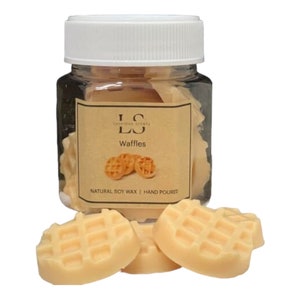 May include: A glass jar filled with small, light orange wax melts shaped like waffles. The jar has a white lid and a label that says "LS" and "Waffles". The label also says "Natural Soy Wax | Hand Poured".