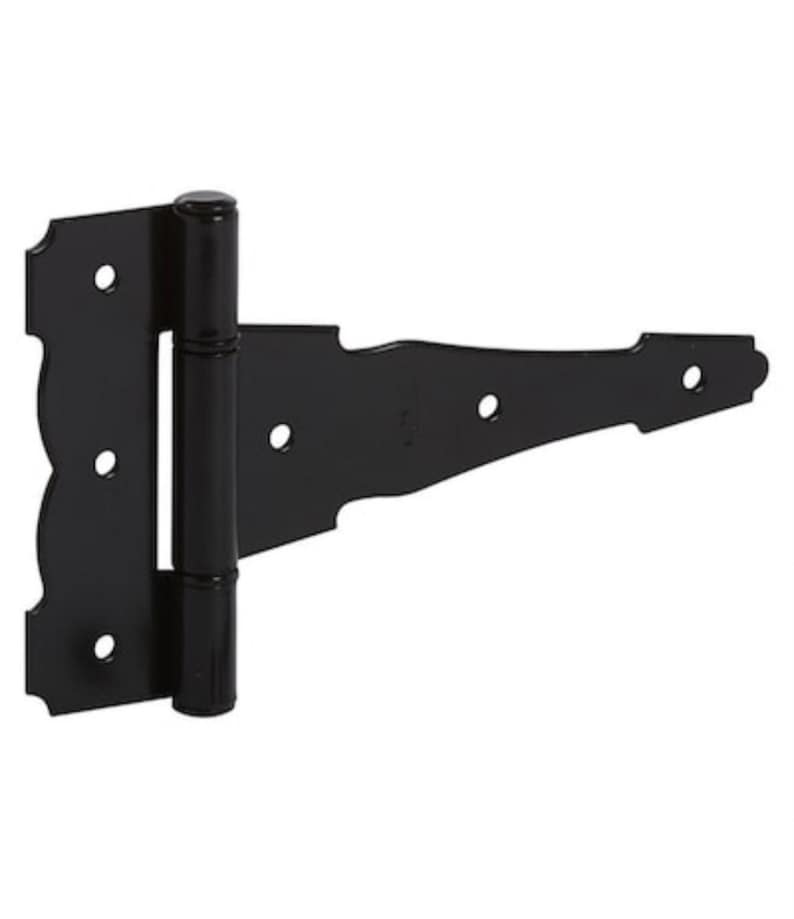 May include: A black metal T-hinge featuring a decorative scalloped edge on the mounting plate and a long, tapered strap. The hinge includes a central cylindrical barrel and five pre-drilled circular holes for installation hardware.