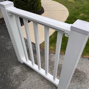 May include: A white vinyl railing section featuring two square posts with flat caps, a horizontal top rail, and a horizontal bottom rail connected by four vertical balusters. The structure is constructed from smooth, solid white material.