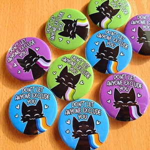 以下が含まれることがあります： 「誰も排除させないで」というテキストと黒い猫のデザインが施された、カラフルなボタンピンが8つ。猫はレインボーのプライドフラッグを持っています。