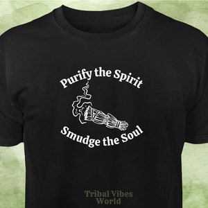 May include: Black t-shirt with white text that reads "Purify the Spirit" and "Smudge the Soul" with a white illustration of a smudge stick and smoke. The text "Tribal Vibes World" is printed in white at the bottom of the shirt.