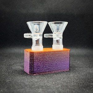 May include: Two clear glass bowls with a purple and orange gradient wooden base. The bowls are connected by a metal bar. The base has the word "Supernova" printed on it.