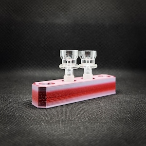 May include: A rectangular, multi-colored holder with two clear glass attachments. The holder transitions from pink to red, with the text "Scarlet Sky" at the bottom. The glass attachments have a flared bowl shape.