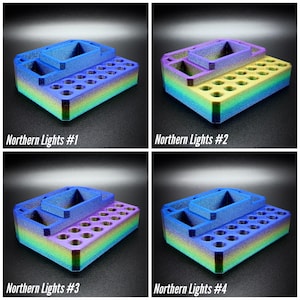 May include: Four multi-colored 3D-printed organizers with the text "Northern Lights #1, #2, #3, #4". Each organizer has a rectangular base with multiple holes and a raised section with two compartments. The colors transition from blue to green to yellow to purple.