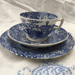 Pode incluir: Um conjunto de chávena e pires de chá azul e branco com um padrão floral. A chávena tem uma pega e o pires tem uma borda ondulada.